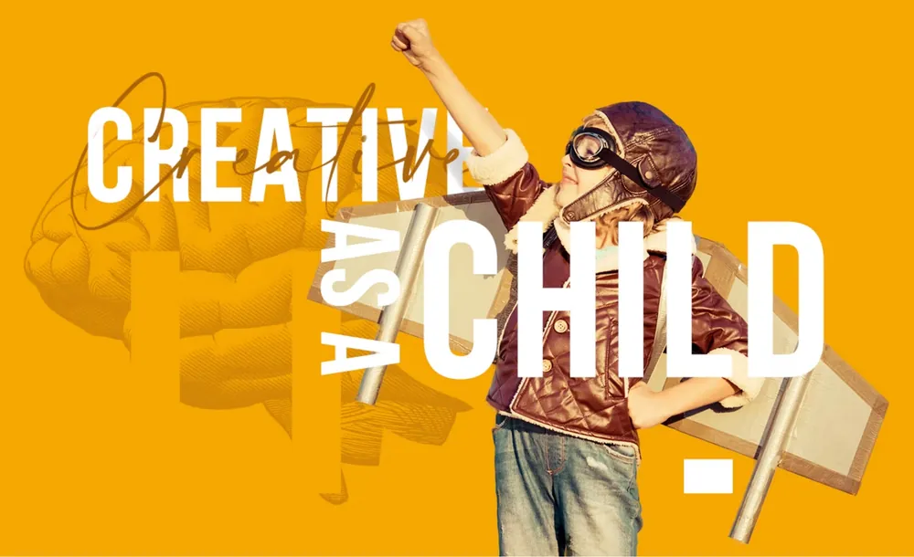 Creative as a child: menino com capacete de aviador e asas de papelão, de punho erguido
